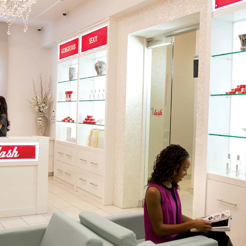 photo of amazing lash studio lobby with a client talking to the front desk and another woman reviewing a catalog