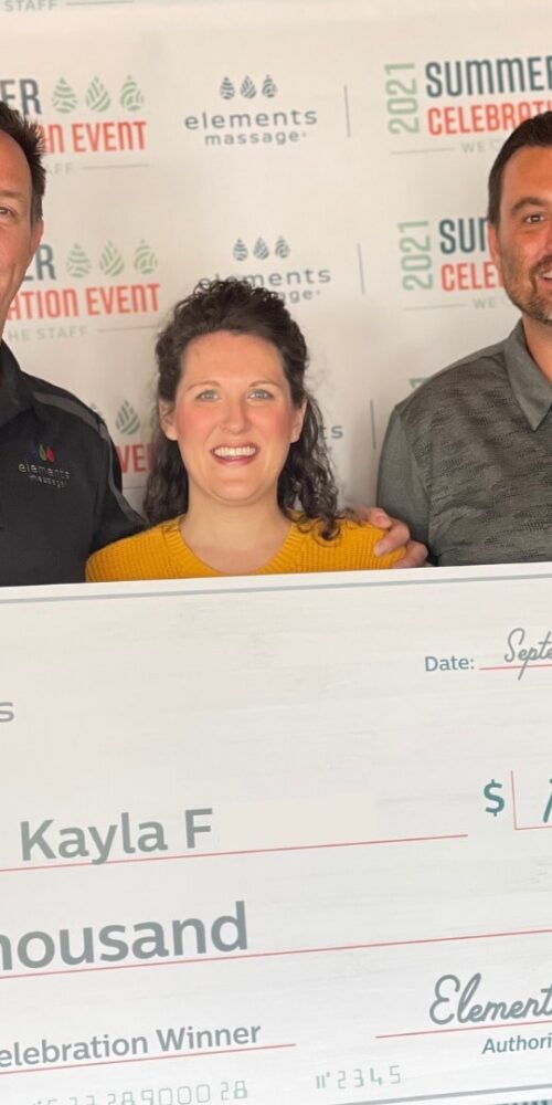 Kayla F along with 2 other men holding a large check fpor the amount of ten thousand dollars from elements massage
