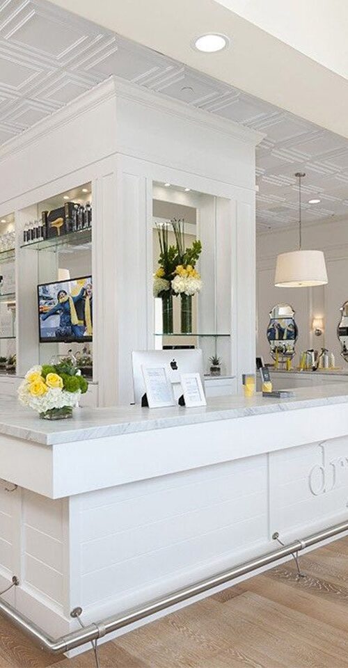 Drybar centered reception desk connected to bar table surrounded by client chairs